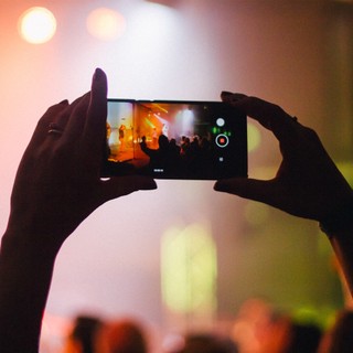Person records a concert on their mobile device at night
