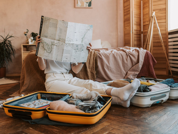 Woman packing suitcase and reading map
